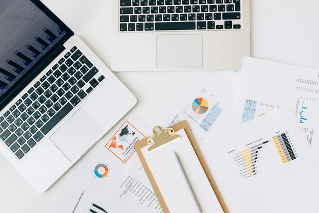 Overhead view of laptops, charts, and reports used for data analysis on a desk. Free web forms and paid panels suit different copywriting services research decisions