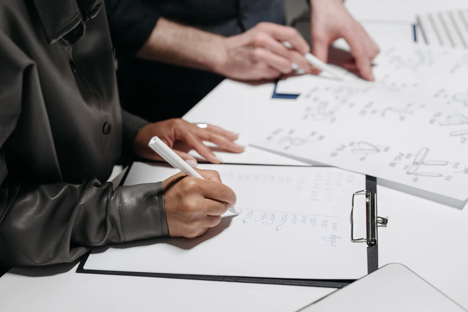 Close-up of team members taking notes and sketching designs during a meeting.