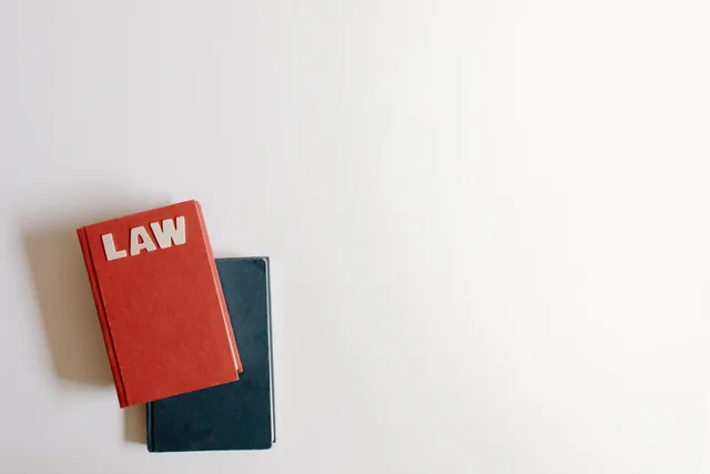 Flat lay of a red law book and a blue book on a white background, perfect for legal themes. Copywriting services rules and ethics, self-regulation or statute?